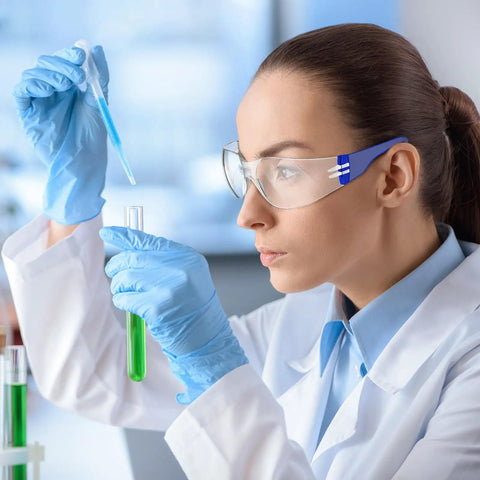 Woman wearing Heavy Duty Safety Glasses Bulk Pack With Clear Lenses And Durable Blue Frames, using a pipette in a lab.