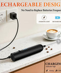 Rechargeable Handheld Milk Frother With 3 Speeds And 3 Stainless Whisks For Coffee, Matcha, Lattes, Cappuccino And More Easy No Fuss Barista Grade Foam Maker For Creamy Froth At Home Black charging on a kitchen counter next to a cappuccino.