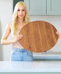 Person holding 21 Inch Acacia Wood Lazy Susan For Tabletop Giant Round Turntable Serving Tray in kitchen setting.