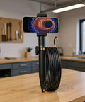 Built Like A Tank Compact Borescope With Flex Head For Snaking Through Tight Conduits On Rough Crewsites Fully Waterproof Industrial Endoscope set on a wooden table.