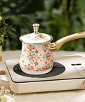 Floral Turkish coffee pot with long wooden handle on electric burner in kitchen setting
