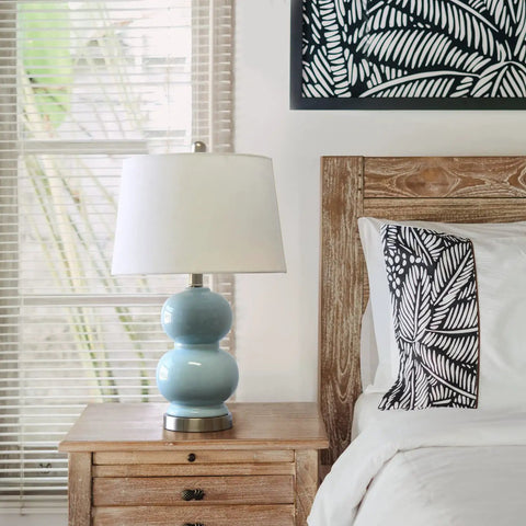 Cool Stacked Stone Double Gourd Ceramic Lamp In Light Blue With White Fabric Shade And Chrome Accents on bedside table