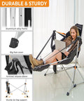Woman relaxing in a heavy-duty hammock chair with footrest for 400 lbs, reading on a laptop, durable aluminum alloy frame.