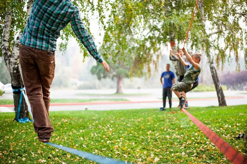 Family using Slackline Kit With Overhead Training Line, Arm Trainer, Tree Protectors during outdoor fun, 60-foot set for all ages