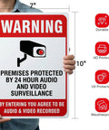 Two Pack Heavy Duty Aluminum Security Warning Signs For Your Property Hella Bright Reflective Red And White Surveillance Notice held by a person, 10x7 inches.