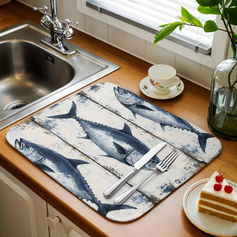 Blue Tuna Oil Painting Dish Drying Mat 18 X 24 Inches on wooden counter next to sink with cutlery and slice of cake.