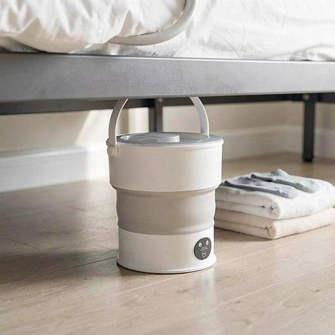 Compact Folding Mini Washing Machine Portable Laundry Basin Road Trip Ready Dorm Staple under bed with folded clothes nearby.