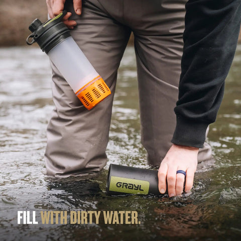Person using GeoPress 24 Oz Water Purifier Bottle For Hiking And Camping, Easy Fill Press Drink System in a river