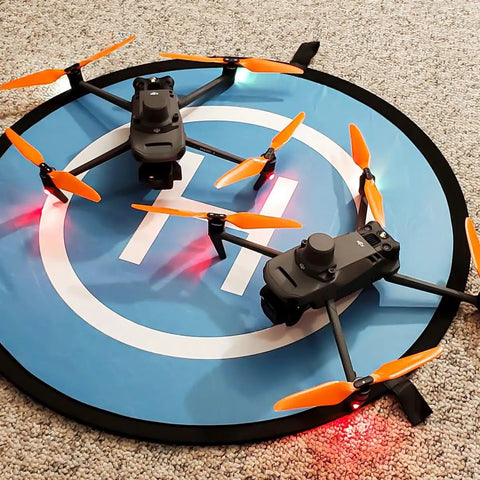 Two DJI Mavic 3 drones with orange Stealth Propellers For DJI Mavic 3 Series Orange 4 Pack Low Noise Up To 2 dB Reduction on blue pad.