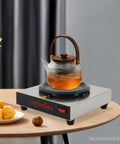 Keep Your Morning Brew Piping Hot With This Rugged Stainless Steel Coffee Warmer Plate Featuring Auto Shut Off And Sturdy Grip Base Built Tough For Corporate Break Rooms Local Diners And Weekend Brunch Stations on a tabletop with a teapot.