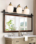 Bold Black And Gold 3 Light Vanity Light Fixture With White Glass Globe in bathroom setting above mirror