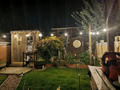 Backyard illuminated with string lights, showcasing M5 Turnbuckle Kit For One Eighth Inch Cable Railing And Wood Posts in use at night