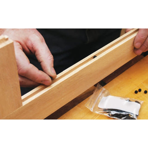 Installing Quarter Inch Rubber Ball Cabinet Door Spacers Auto Center Alignment Tool into wooden rail for smooth fit.
