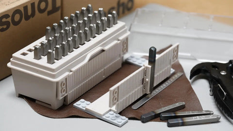 36 Piece Alphabet And Number Stamp Set With Built In Alignment Tools For Precise Imprinting On Metal Plastic And Wood One Eighth Inch 3mm Punch Hardened To HRC 62 With Durable Storage Box Made In USA visible with storage box and tools on a table