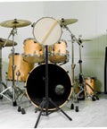 Heavy Duty Alloy Snare Drum Storage Rack And Portable Stand Support For Beginners Quick Lock Setup In Sleek Matte Black Finish, with snare and drum set backdrop.