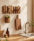 Premium Acacia Wood Wall Mounted Coat Rack With Eight Retractable Hooks, Space Saving Flip Down Entryway Stand, Zero Drama Install And Heavy Duty Grip For The Daily Grind in a kitchen setting, displaying hooks and a cutting board.