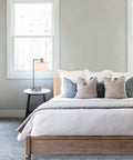 Lit Brushed Nickel USB Desk Lamp With White Fabric Shade next to a bed in a modern bedroom