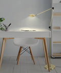 Sage 2 In 1 LED Craft Table And Floor Lamp Adjustable Floor Reading Light in gold by desk, 360 rotatable head, living room setting.