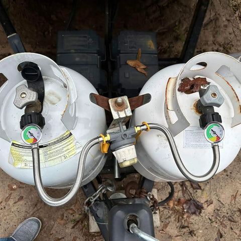 Dual propane tanks connected by 15 Inch RV Propane Hose With Gauge Stainless Steel Braided Camper Gas Hose 2 Pack One Quarter NPT Male To QCC1 Quick Connect For Your RV Setup Upgraded Gauge With Weather Readout For Accurate Readouts.