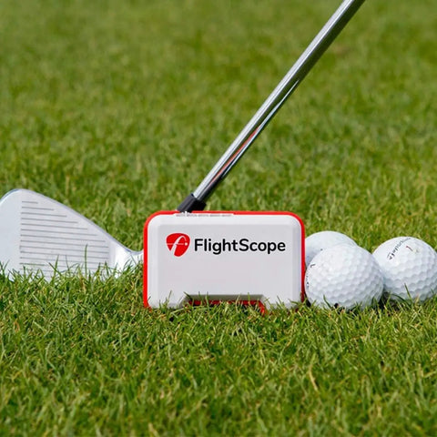 Portable Golf Launch Monitor Mevo with 3D Doppler Radar on grass with golf club and balls