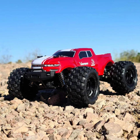 Red Volcano One Sixteenth Scale RC Monster Truck With Four Wheel Drive on rocky terrain, showcasing its large tires and rugged design.