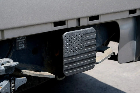 Patriotic 2 Inch Tow Hitch Cover Plug With American Flag Design attached to a truck, showing top view with textured flag pattern.