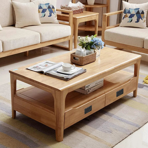 Wooden coffee table with storage drawers in a cozy living room setting with sofas and decorations.