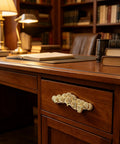Two Pack Golden Welcoming Pine Cabinet Handles For Vintage Dressers And Drawers on a wooden desk drawer in a library setting.