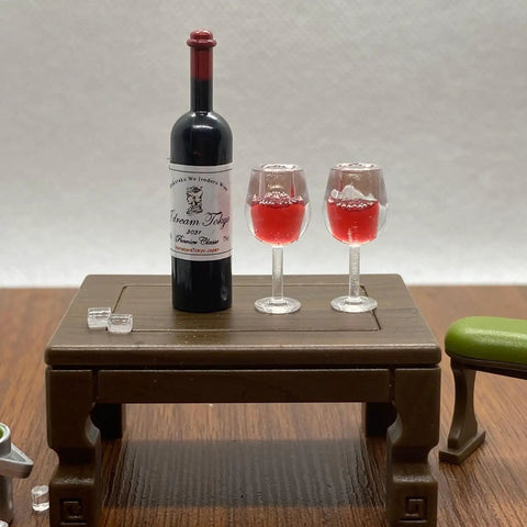 Hella Cool Miniature Red Wine Bottle Set Featuring Two Resin Filled Wine Glasses And A Static Corkscrew For Dollhouse Decor on table