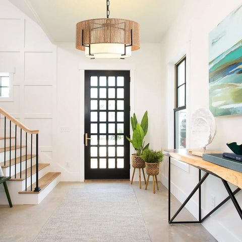 A Straight Up Game Changer 4Light Rattan Chandelier With Linen Drum Shades illuminates the entryway with a boho vibe and soft lighting.
