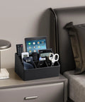 Straight Up Sturdy PU Leather Desk Organizer With Five Compartments Sleek Black Design containing phones and scissors on a bedside table.