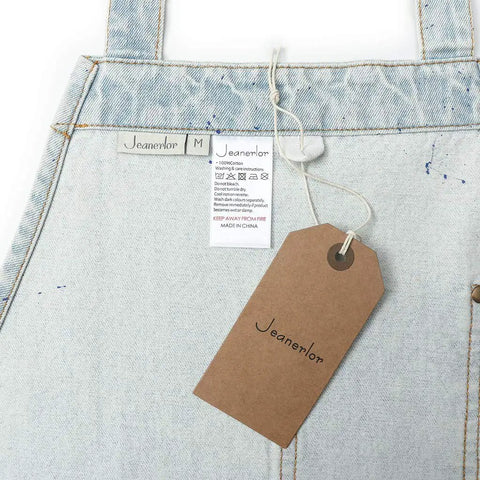Close-up of Denim Tool Shop Apron For Hairstylists With Five Pockets, Cross Back Straps, Adjustable From S To M, tag visible.