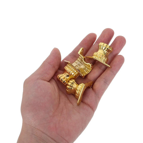 Hand holding antique metal box feet corner protectors set of 20 for jewelry boxes and wood cases, old school retro style.