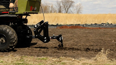 Middle Buster Furrower Attachment For Subsoil Work From Impact Implements in action on farm, tractor hookup visible, durable steel design
