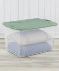 Six Pack Sage Green Storage Bins 66 Quart Clear Stackable Plastic Containers With No Sweat Snap Lock Design Stack Smart For Clothes Moving Garage And Serious Organizing with a pillow and blanket inside.
