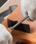 Close-up of hands using the sharpener on the Top Shelf Six Piece Cabinet Scraper And Burnisher Kit With Blue Spring Steel Blades Plus Hardened High Speed Steel Sharpening Rod For Knockout Woodworking Finishes Daily.