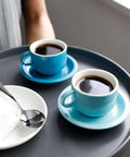 Two blue espresso cups on saucers with a Demitasse Espresso Spoon Set Of 6, Mini Stainless Steel Coffee Spoons, on a tray.