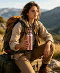 Person holding Copper Water Bottle 800ml Insulated Travel Cup With Anti Slip Grip, perfect for camping and hiking outdoors.