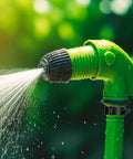 Green garden hose nozzle spraying water with adjustable spray pattern