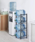 Heavy Duty 4 Tier Water Jug Rack for 5 Gallon Jugs Detachable Black Metal Bottle Holder next to a water dispenser in office
