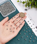 Close-up of hand holding antique silver tube spacer beads, 300 pcs, Tibetan zinc alloy, 4x5mm with 2.2mm hole. Ideal for DIY jewelry.