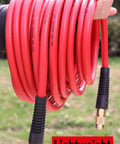Hand holding red Heavy Duty Hybrid Air Hose 1 Quarter Inch By 100 Feet, 300 PSI, Lightweight And Kink Resistant with couplers.