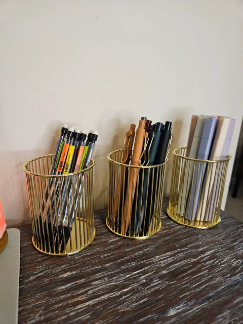 Gold Metal Two Pack Sticky Note Holder And Pen Holder Set with circle design on a desk holding pens and pencils.