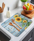 MustHave Kitchen Dish Drying Mat 18x24 with sunflower bee design on blue wood grain, on countertop with utensils