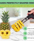 Front view of pineapple corer and slicer with stainless steel shaft and black handle cutting pineapple into rings.