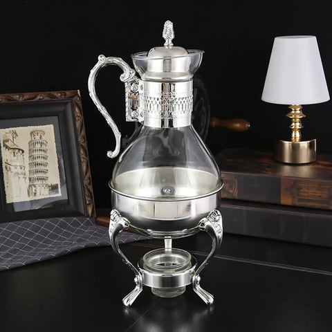 Glass Teapot With Warmer 50 Oz Vintage Espresso Kettle Heats Up Coffee Pot With Handle Heat Resistant Turkish Coffee Pitcher Teapot For Your Home Office Cafe Vibe Silver on a table with a lamp and framed picture in the background.