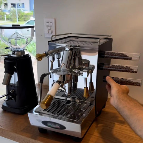 Keep Your Grind Fresh With This Premium Airtight Coffee Bean Storage Tube Set Featuring Four Smart Glass Jars And Clean Counter Display showing espresso machine and glass jar set.