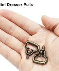 Hand holding antique bronze mini dresser pulls from 20 Pack Mini Bronze Cabinet Handles Set With Self Tapping Screws Zinc Alloy.