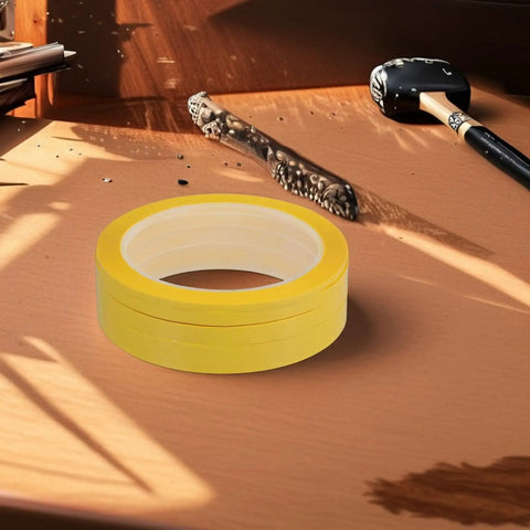 Four Pack Yellow Heat Resistant Paper Tape featuring a dang tough hold on a wooden desk with tools, ideal for neat labeling and organizing.