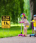 Slow Down Signs With H Stake 16x12 Inches Kids And Pets At Play Double Sided Street Safety Signs in use by sidewalk with children playing.